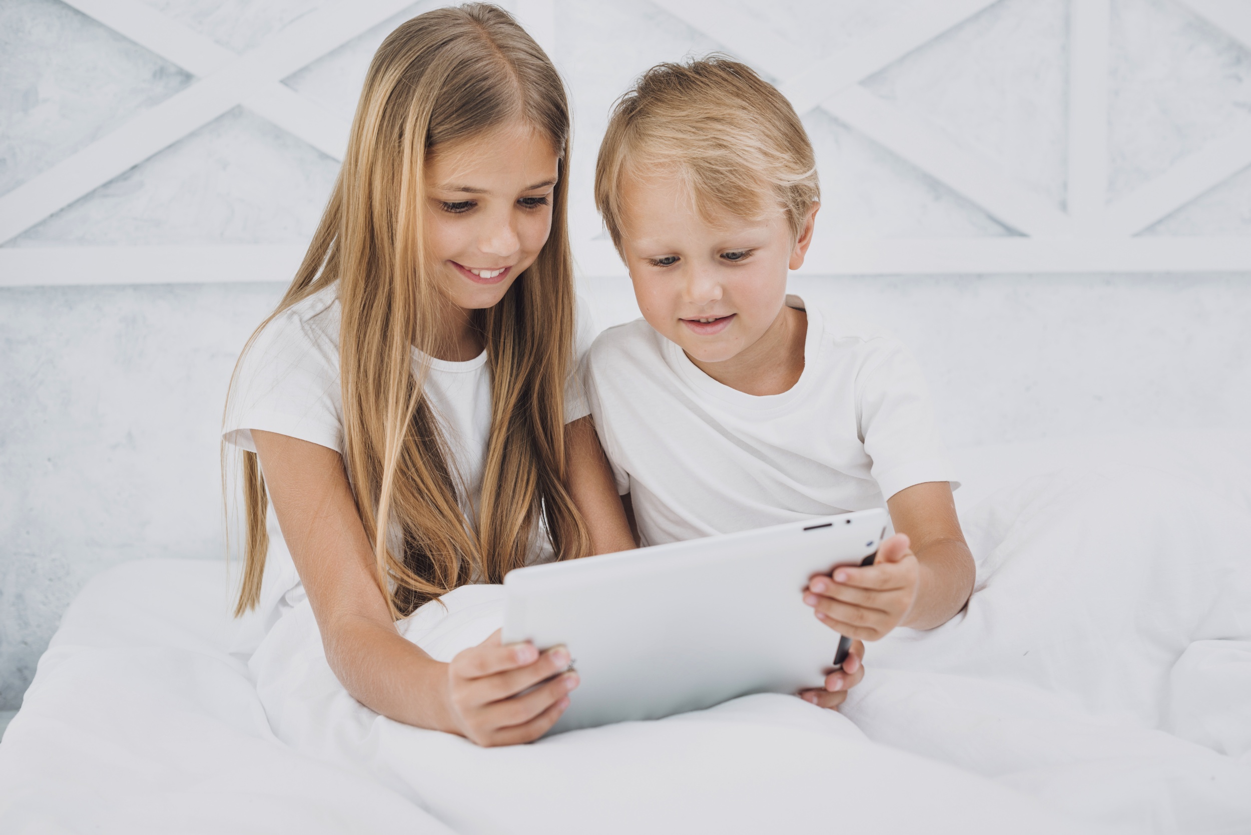 front-view-siblings-staying-bed-while-playing-tablet.jpg